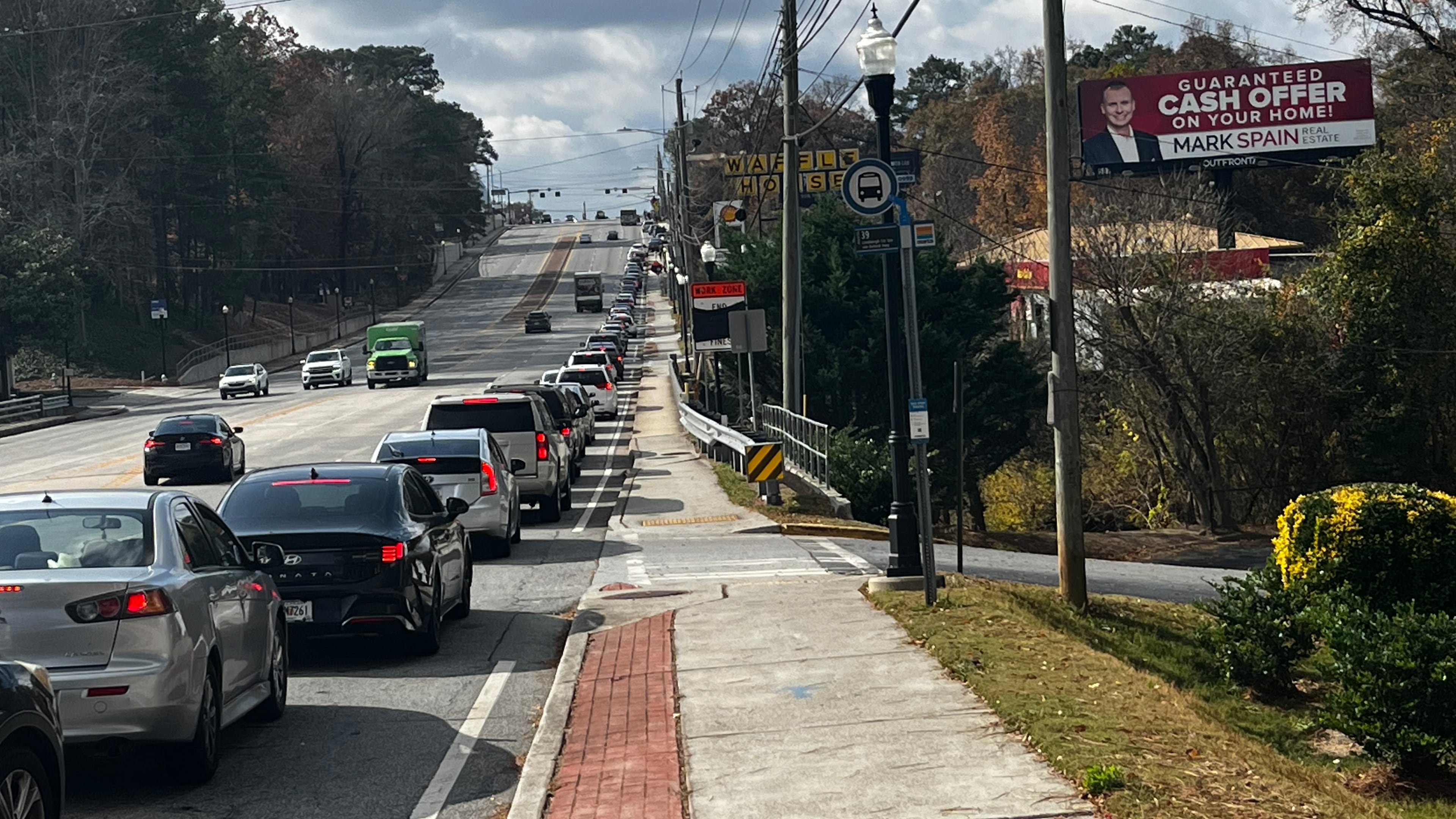 A line of cars on Buford Highway makes it way to the Latin American Association, site of a food distribution event, on Saturday, Nov. 22, 2025. Dozens of community members also made their way on foot. (Lautaro Grinspan/AJC)