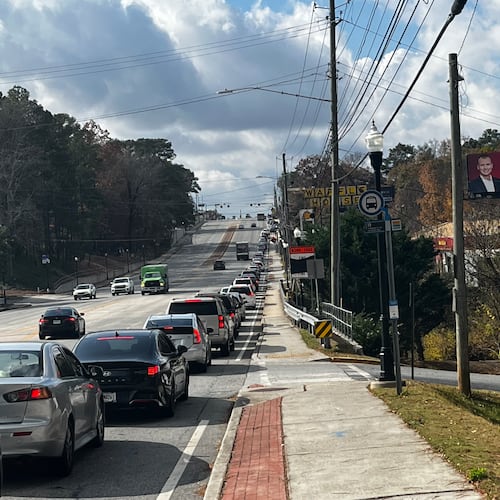 A line of cars on Buford Highway makes it way to the Latin American Association, site of a food distribution event, on Saturday, Nov. 22, 2025. Dozens of community members also made their way on foot. (Lautaro Grinspan/AJC)