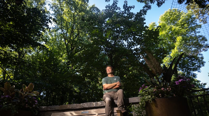 Scott McMahan, vice president of horticulture and collections, sits in front of a rare Chinese emmenopterys henryi tree at Atlanta Botanical Garden. (Arvin Temkar/AJC)