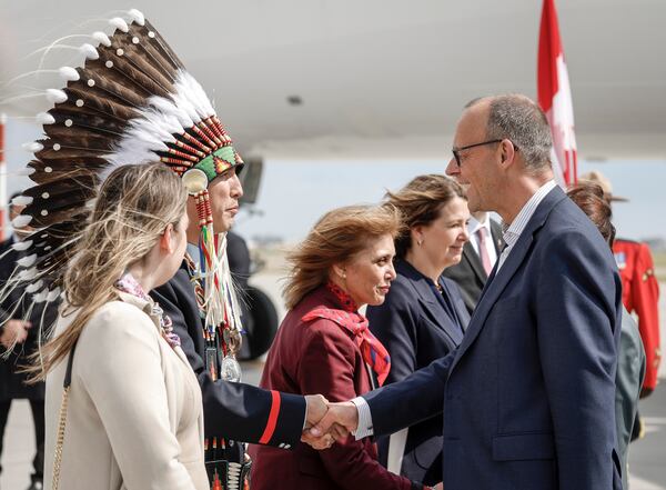 German Chancellor Friedrich Merz, right, is greeted by Steven Crowchild, second left, of the Tsuut'ina First Nation, as he arrives in Calgary, Alberta, Sunday, June 15, 2025, to attend the G7 Leaders meeting taking place in Kananaskis. (Jeff McIntosh/The Canadian Press via AP)