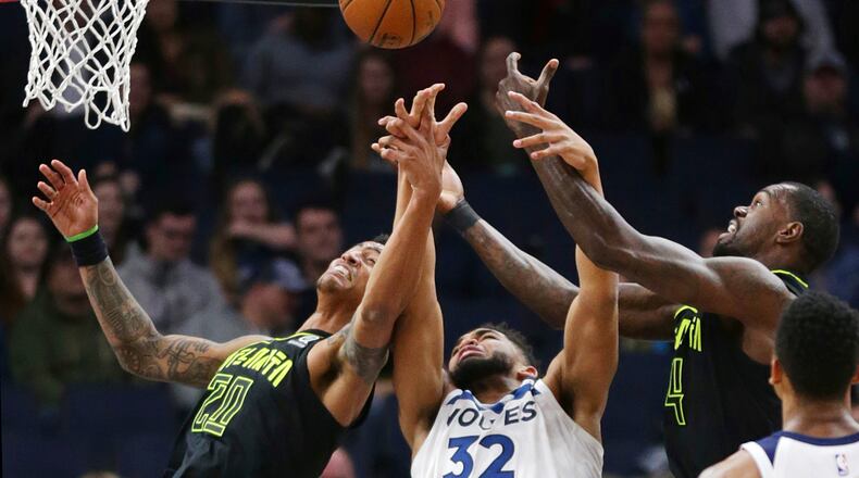 Minnesota Timberwolves forward Karl-Anthony Towns (32) vies for a rebound with Atlanta Hawks forwards Dewayne Dedmon (14) and John Collins (20) during the first quarter of an NBA basketball game Wednesday, March 28, 2018, in Minneapolis. (AP Photo/Andy Clayton-King)