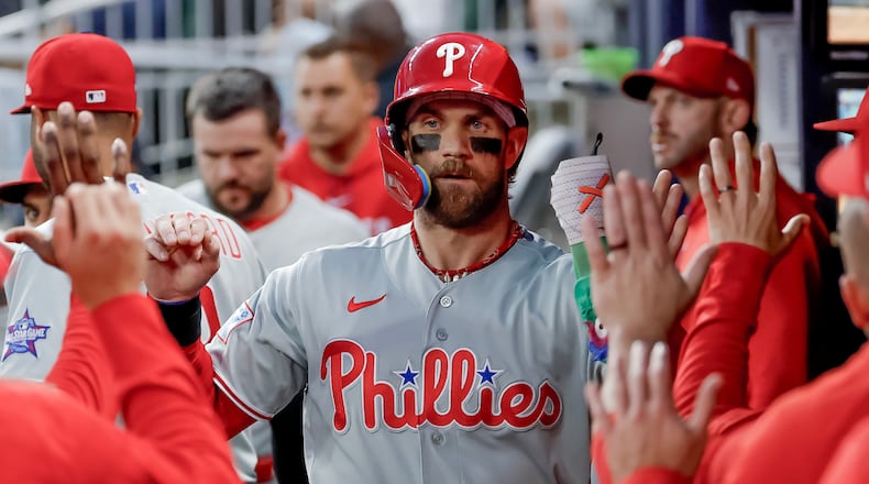 Philadelphia Phillies' Bryce Harper is greeted in the dugout after scoring against the Atlanta Braves during the first inning of a baseball game, Saturday, April 25, 2026, in Atlanta. (AP Photo/Erik S. Lesser)