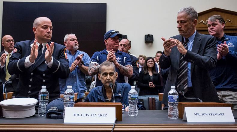 WASHINGTON, DC - JUNE 11: Retired Fire Department of New York Lieutenant and 9/11 responder Michael O'Connelll, left, FealGood Foundation co-founder John Feal, center, and former Daily Show Host Jon Stewart, right, applaud following testimony from Retired New York Police Department detective and 9/11 responder Luis Alvarez during a House Judiciary Committee hearing on reauthorization of the September 11th Victim Compensation Fund on Capitol Hill on June 11, 2019 in Washington, DC.