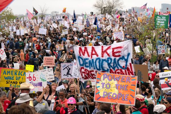 Demonstrators hold up signs during a "Hands Off!" protest against President Donald Trump at the Washington Monument in Washington, Saturday, April 5, 2025. (AP Photo/Jose Luis Magana)