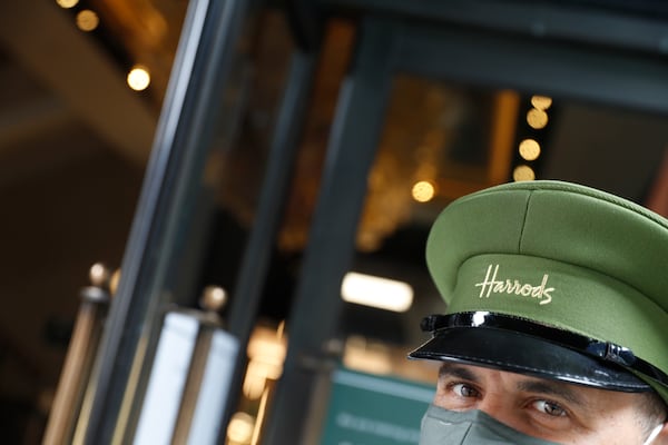 FILE - A doorman wearing a mask outside Harrods department store opens the door for customers in London, Wednesday, July 1, 2020. (AP Photo/Alastair Grant, file)
