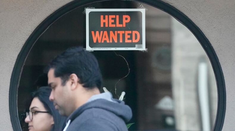 FILE - Pedestrians walk past a help wanted sign posted on the door of a restaurant in San Francisco, Tuesday, April 18, 2023. (AP Photo/Jeff Chiu, File)