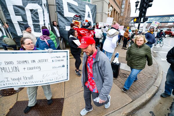 Protesters hold signs as people arrive for a town hall with Elon Musk, Sunday, March 30, 2025, in Green Bay, Wis. (AP Photo/Jeffrey Phelps)