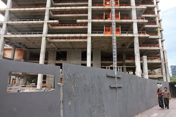 Pedestrians walk past the Campanile building on Peachtree Street NE and 14th Street in Atlanta on May 22, 2026. The building has remained incomplete for years and locals are unhappy with the slow progress. (Arvin Temkar/AJC)