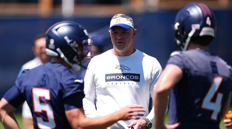 FILE - Denver Broncos offensive coordinator Joe Lombardi, center, confers with Denver Broncos quarterbacks Ian Book (5) and Blake Stenstrom (4) as they take part in drills during the NFL football team's rookie minicamp, May 10, 2025, in Centennial, Colo. (AP Photo/David Zalubowski, File)