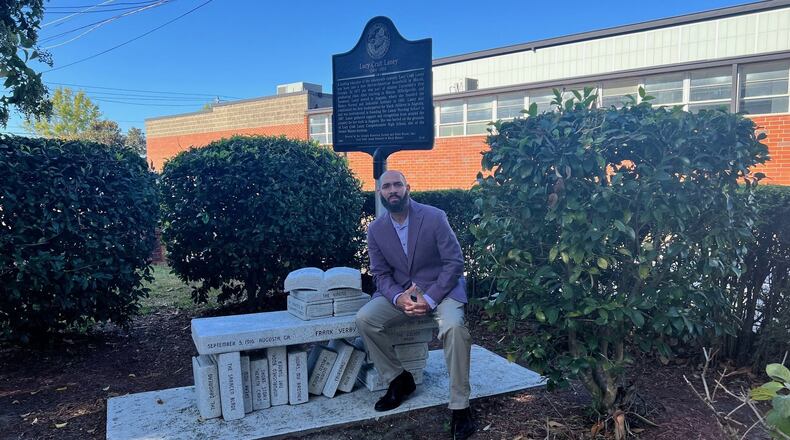 Corey Rogers sits a on bench highlighting the works of author Frank Yerby in the courtyard of the Lucy Craft Laney Museum of Black History. (Charmain Brackett/Augusta Good News)