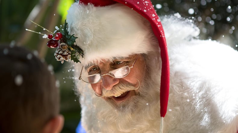 Santa Claus Keith Carson, of the Believe in Santa Foundation, visits children during a Christmas in July event at Palm Beach Children's Hospital on Friday, July 25, 2014 in West Palm Beach. Fake snow floated through the hospital courtyard and Santa Claus went room-to-room to deliver presents. (Madeline Gray / The Palm Beach Post)