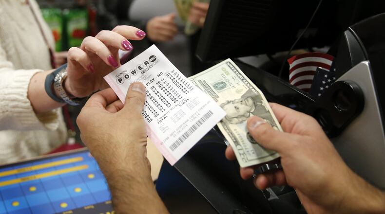 Biren Shah, right, sells a Powerball lottery ticket to a patron at his news stand as the multi-state jackpot reaches $800 million, Friday, Jan. 8, 2016, in Chicago. With ticket sales doubling previous records, the odds are growing that someone will win Saturday’s record jackpot, but if no one wins the top prize, next week’s drawing is expected to soar past $1 billion. (AP Photo/Charles Rex Arbogast)