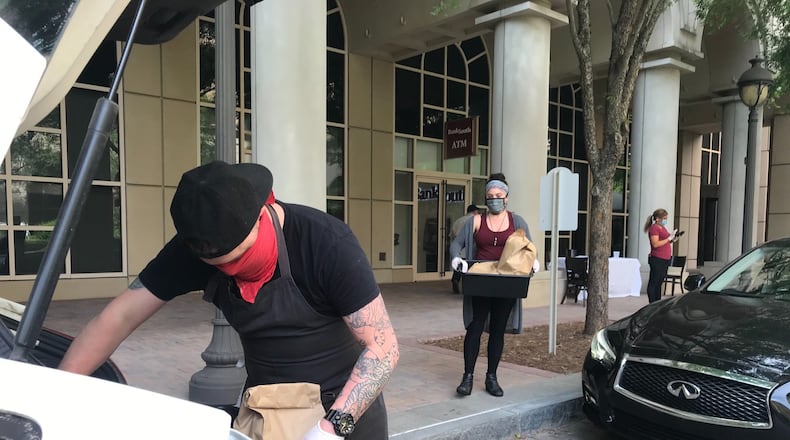 Local Three employees Carter Vaughn and Kelli Bullock bring orders for curbside pickup at the upscale Buckhead restaurant. LIGAYA FIGUERAS / LIGAYA.FIGUERAS@AJC.COM
