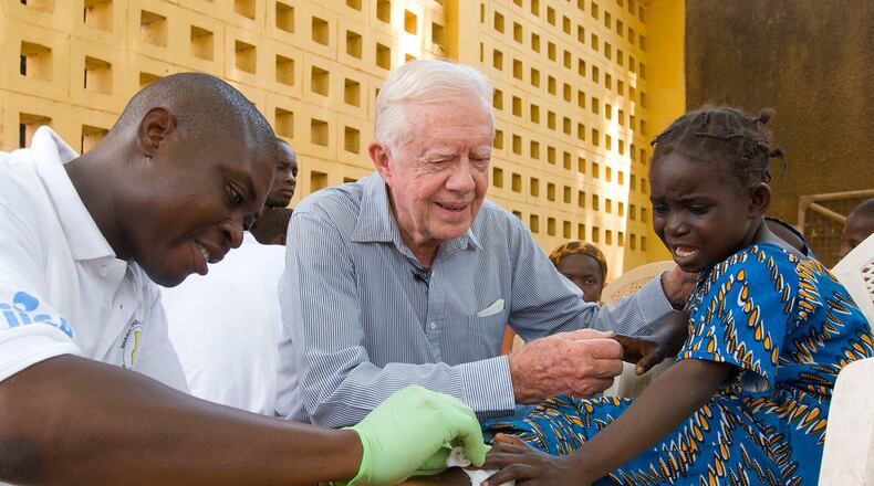 Jimmy Carter consoles a young patient having a Guinea worm removed from her body in Savelugu, Ghana, in February 2007. The Carter Center led the international campaign to try to eradicate Guinea worm disease. (Louise Gubb/The Carter Center/TNS)