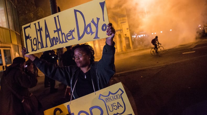 A protester in Baltimore holds up a sign as police enforce a citywide curfew of 10 p.m. after the funeral of Freddie Gray in late April. Gray, 25, was arrested for possessing a switch-blade knife April 12 outside a housing project on Baltimore’s west side. He died a week later from a severe spinal cord injury he suffered while in police custody. (Photo by Andrew Burton/Getty Images)
