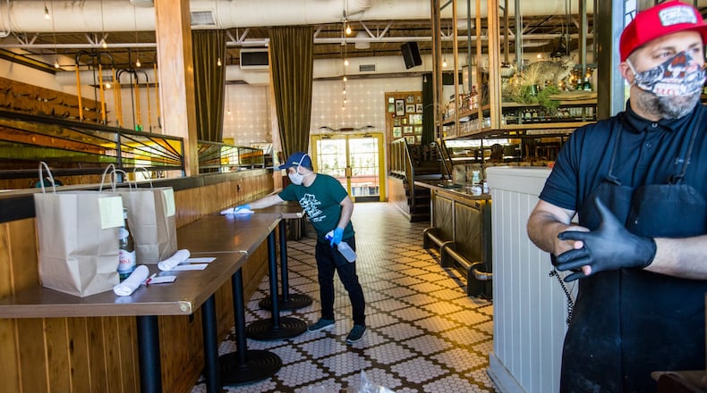 Josh Ardizzoni, the maitre d’ at Marcel, left, sanitized surfaces every hour while he worked the front at Superica in Alpharetta with Andy Palermo, right, the Director of Operations at Superica, who put his gloves back on after his hourly hand washing on Wednesday, March 25, 2020. The staff prepped food in take-out containers to serve drive-up customers with limited contact. The next day, Ford Fry’s Rocket Farm Restaurants group closed all 17 of its restaurants completely, including Superica. (Jenni Girtman for The Atlanta Journal Constitution)