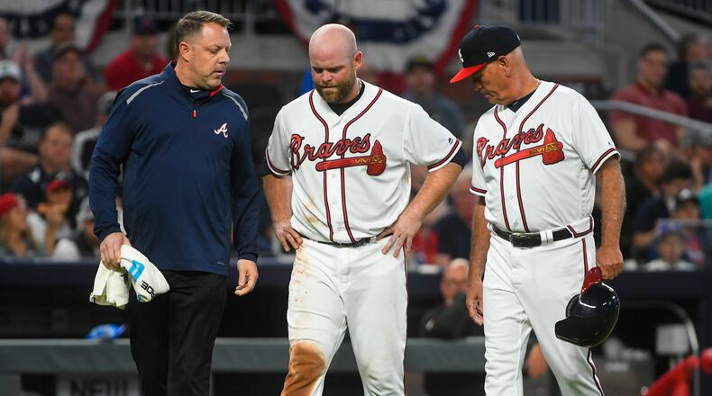 Atlanta Braves catcher Brian McCann (center) comes off the field with manager Brian Snitker (right) and trainer Mike Frostad after being thrown out sliding into third by Miami Marlins catcher Jorge Alfaro on a bunt by Kyle Wright during the fifth inning of a baseball game Saturday, April 6, 2019, at SunTrust Park in Atlanta.