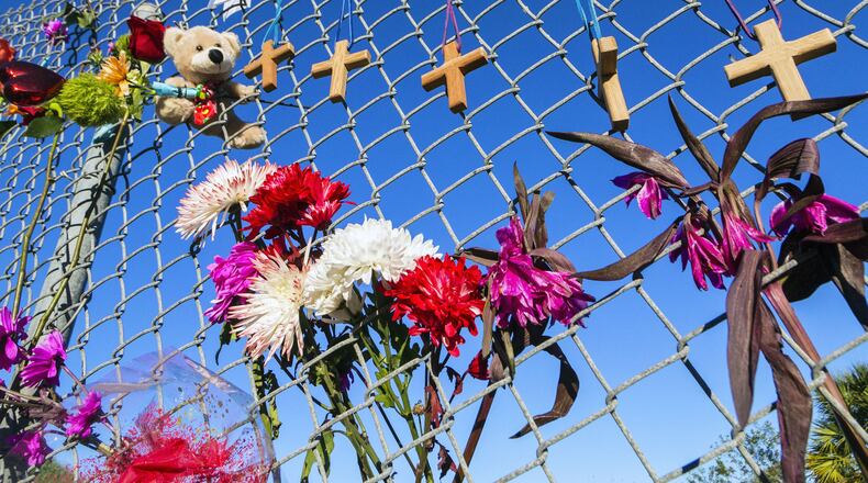 Crosses and flowers hang on a fence outside Marjory Stoneman Douglas High School in Parkland, Florida, in memory of the 17 people killed in a shooting. Attorneys for the man accused of killing 17 people at a Florida high school in 2018 want a judge to close all future hearings to the media and the public to ensure a fair trial. (AJC file photo)
