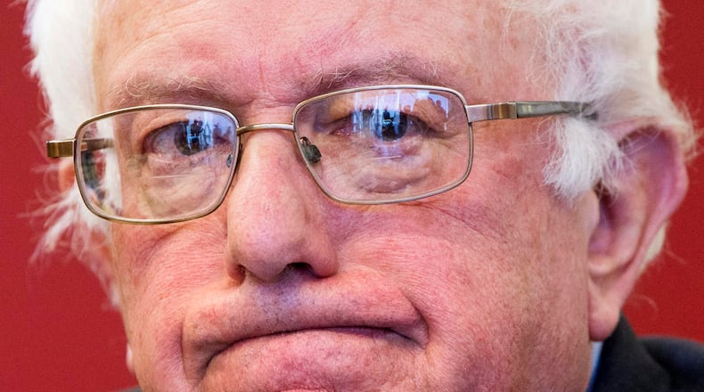 Listening journalists and television cameras are reflected in the glasses of Democratic presidential candidate, Sen. Bernie Sanders, I-Vt. as he meets with leaders of nine historic civil rights groups, at the National Urban League Washington Bureau in Washington on Thursday Feb. 18, 2016. (AP Photo/Jacquelyn Martin)