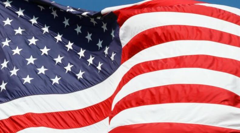 The flag of the United States of America waves in the wind against a deep blue sky (stock photo).
