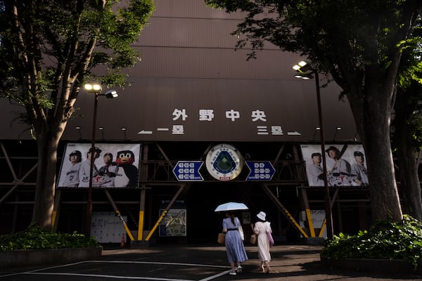 Visitors walk past the Jingu stadium in Tokyo, Monday, June 30, 2025. (AP Photo/Louise Delmotte)
