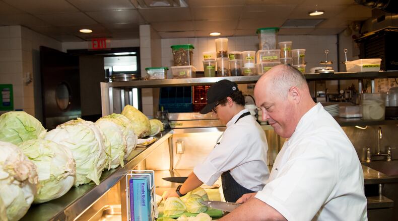 Chef Linton Hopkins and son Linton Hopkins Jr. chop cabbage for sauerkraut at Restaurant Eugene. CONTRIBUTED BY MIA YAKEL