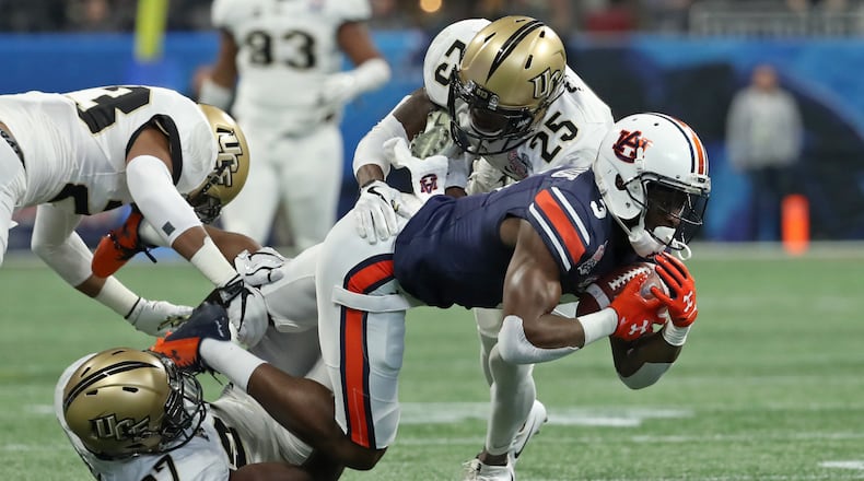 January 1, 2018 - Atlanta, Ga: Auburn Tigers wide receiver Nate Craig-Myers (3) is tackled by UCF Knights defensive back Richie Grant (27) and defensive back Kyle Gibson (25) after a catch by Craig-Myers during the first quarter of the Chick-fil-a Peach Bowl at the Mercedes-Benz Stadium Monday, January 1, 2018, in Atlanta. PHOTO / JASON GETZ
