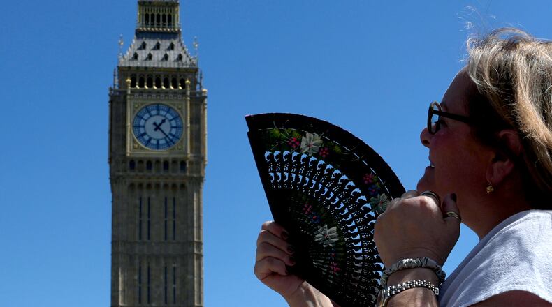 FILE - A woman cools herself outside the Palace of Westminster in London, May 26, 2026. (AP Photo/Kin Cheung, File)