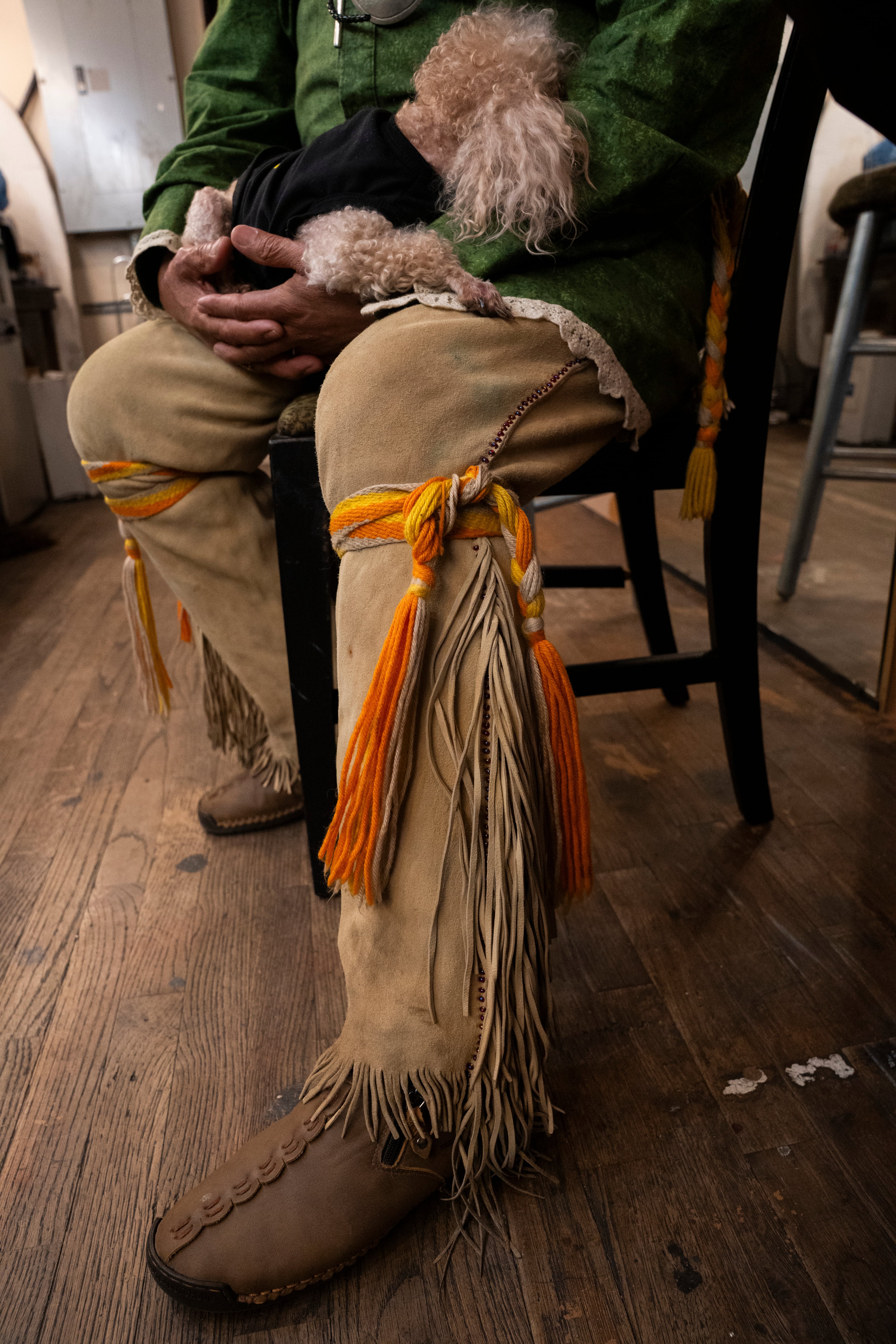 Muscogee (Creek) elder William Harjo waits backstage to perform during the Art of Activism program at 7 Stages Theatre in Atlanta on Friday, Nov. 14, 2025. He is wearing traditional buckskin leggings with long fringe secured by hand-woven wool leg garters. (Olivia Bowdoin for the AJC)