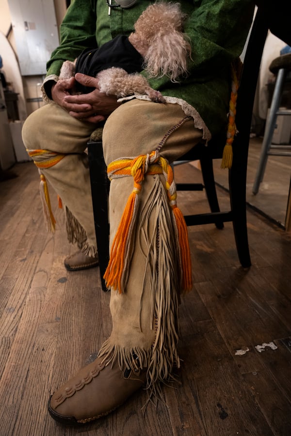 Muscogee (Creek) elder William Harjo waits backstage to perform during the Art of Activism program at 7 Stages Theatre in Atlanta on Friday, Nov. 14, 2025. He is wearing traditional buckskin leggings with long fringe secured by hand-woven wool leg garters. (Olivia Bowdoin for the AJC)