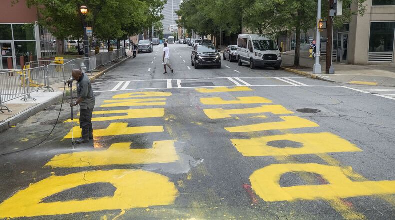 A City of Atlanta employee pressure washes the phrase “Defund Police” written in front of the Atlanta Police Department Headquarters, at the intersection of Garnett Street SW and Pryor Street SW, Wednesday, June 10, 2020. (ALYSSA POINTER / ALYSSA.POINTER@AJC.COM)