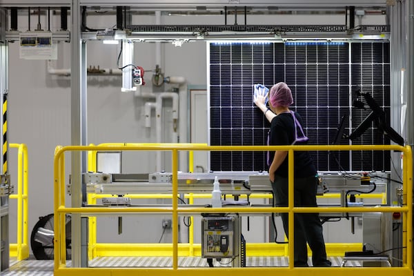 A worker wipes solar panels at the Qcells solar factory in White on June 8, 2026. (Arvin Temkar/AJC)