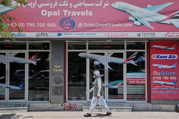 An Afghan person passes in front of an air travel agency in Kabul, Afghanistan, Thursday, June 5, 2025. (AP Photo/Ebrahim Noroozi)