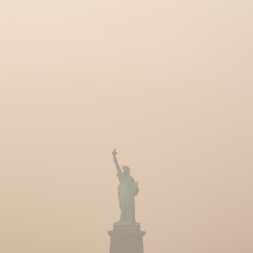 The Statue of Liberty is photographed from the Staten Island Ferry as smoke from wildfires blankets the sky, Thursday, July 16, 2026, in New York. (AP Photo/Yuki Iwamura)