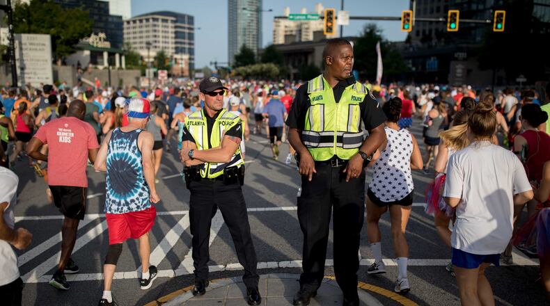 Atlanta Police officers keep watch as runners make their way down Peachtree Street during the 48th AJC Peachtree Road Race, Tuesday, July 4, 2017, in Atlanta. BRANDEN CAMP/SPECIAL
