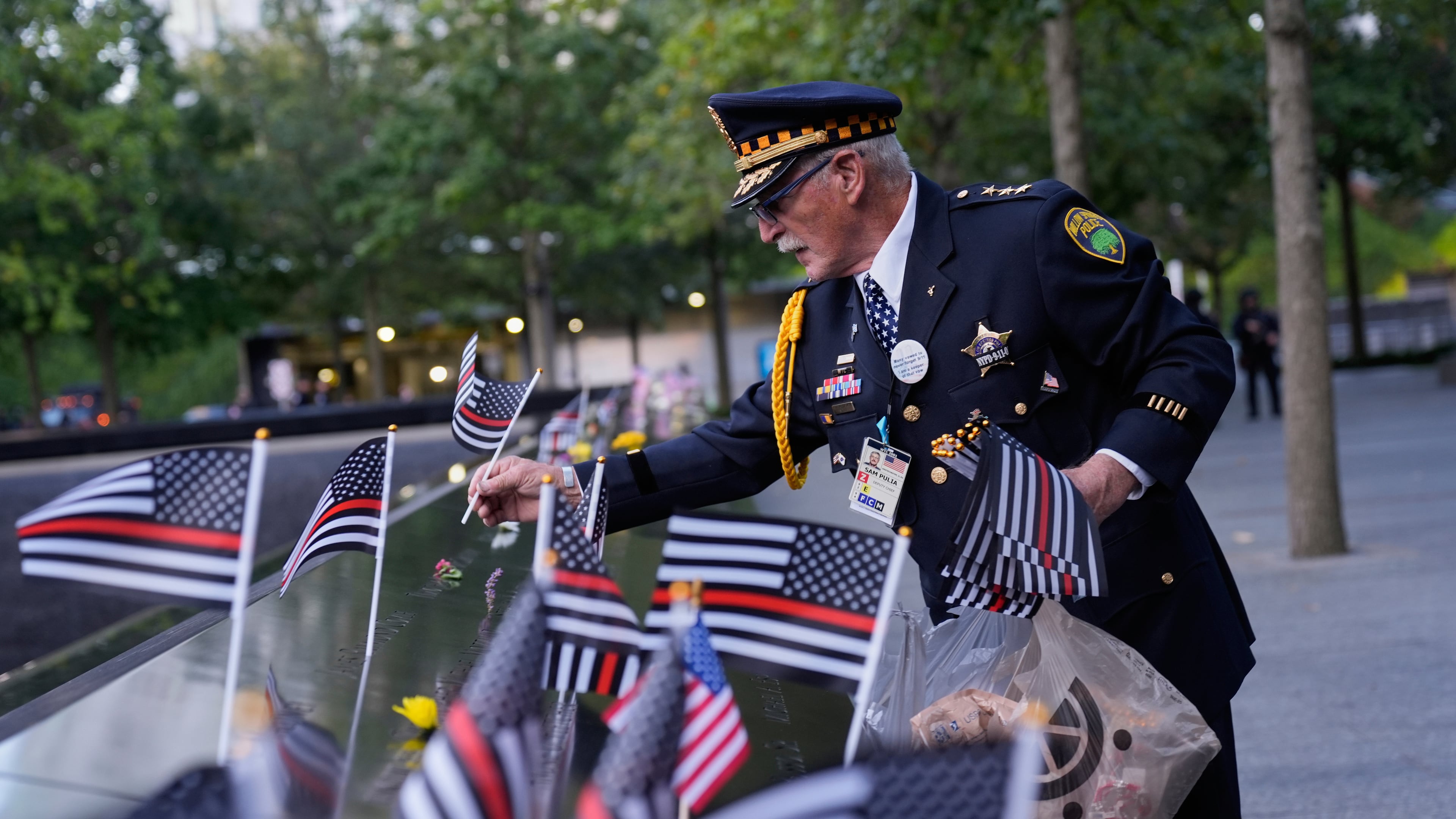 Sam Pulia places flags on names inscribed in the 9/11 Memorial before the start of a ceremony commemorating the 24th anniversary of the Sept. 11, 2001, attacks, Thursday, Sept. 11, 2025, in New York. (AP Photo/Seth Wenig)