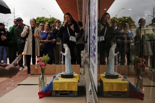 People pray near an altar set up outside the clinic where Colombian Senator Miguel Uribe Turbay is being treated after being shot at a political rally, in Bogota, Colombia, Tuesday, June 10, 2025. (AP Photo/Ivan Valencia)