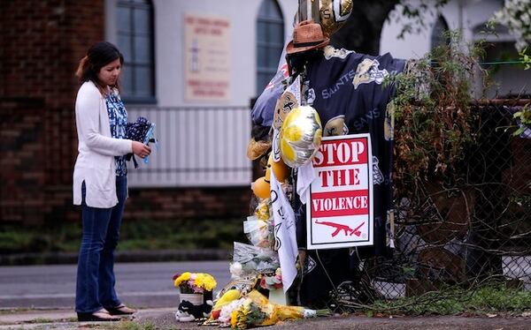 Gabriella Ortiz of New Orleans pauses at a makeshift memorial in New Orleans on April 12, 2016, near the spot where former Saints defensive end Will Smith was shot and killed, and his wife wounded by gunfire, after a traffic accident. (AP Photo/Gerald Herbert)