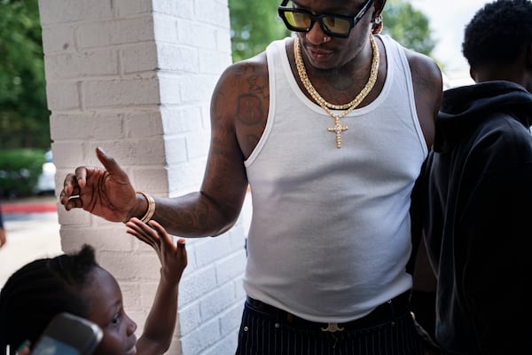 Rapper Jeffery Williams, known as Young Thug, high-fives a young girl during his visit to Skyview High School, Friday, Aug. 1, 2025, in College Park. The appearance, part of his court-mandated anti-gang outreach, brought students and community members together for a rare and personal interaction with the artist. (Olivia Bowdoin for the AJC)