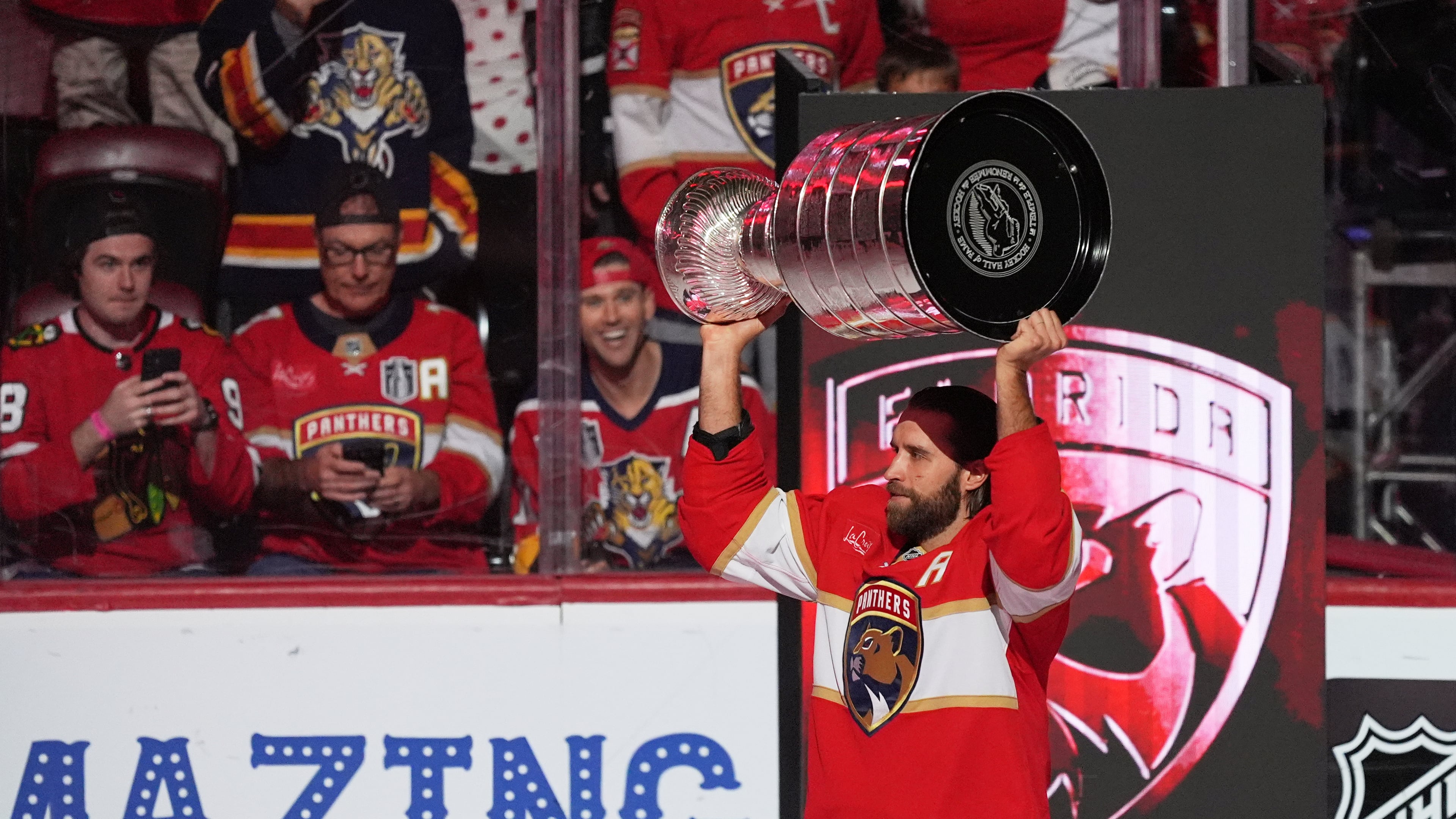 Florida Panthers defenseman Aaron Ekblad holds up the Stanley Cup as he arrives on the ice for the home opener NHL hockey game of the 2025 Stanley Cup champions, against the Chicago Blackhawks, Tuesday, Oct. 7, 2025, in Sunrise, Fla. (AP Photo/Rebecca Blackwell)