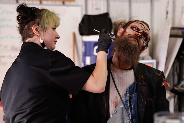Makeup artist Amber Cochran airbrushes Brian Scott Gordon’s face to create the Farmer Jenkins character for Fright Fest at Six Flags Over Georgia on Friday, Sept. 26, 2025. (Natrice Miller/AJC)