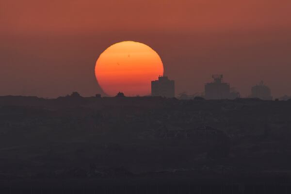 Destroyed buildings in the Gaza Strip are silhouetted in front of the setting sun in southern Israel, Thursday, May 29, 2025. (AP Photo/Ohad Zwigenberg)