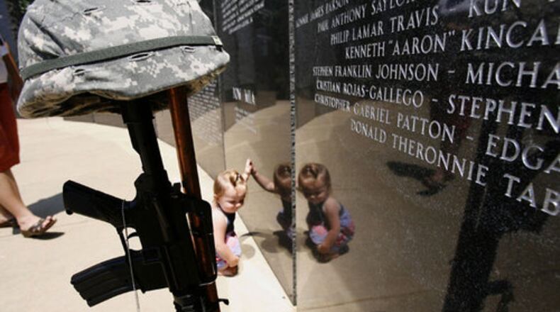 Kirin Murad leans on the granite wall for support during Lawrenceville's annual Memorial Day ceremony at the Gwinnett Fallen Heroes Memorial. The county will hold a virtual ceremony this year. AJC FILE PHOTO