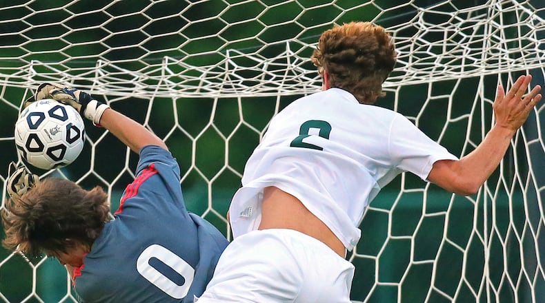 Westminster and Lovett goalkeeper players collide during a soccer match.
