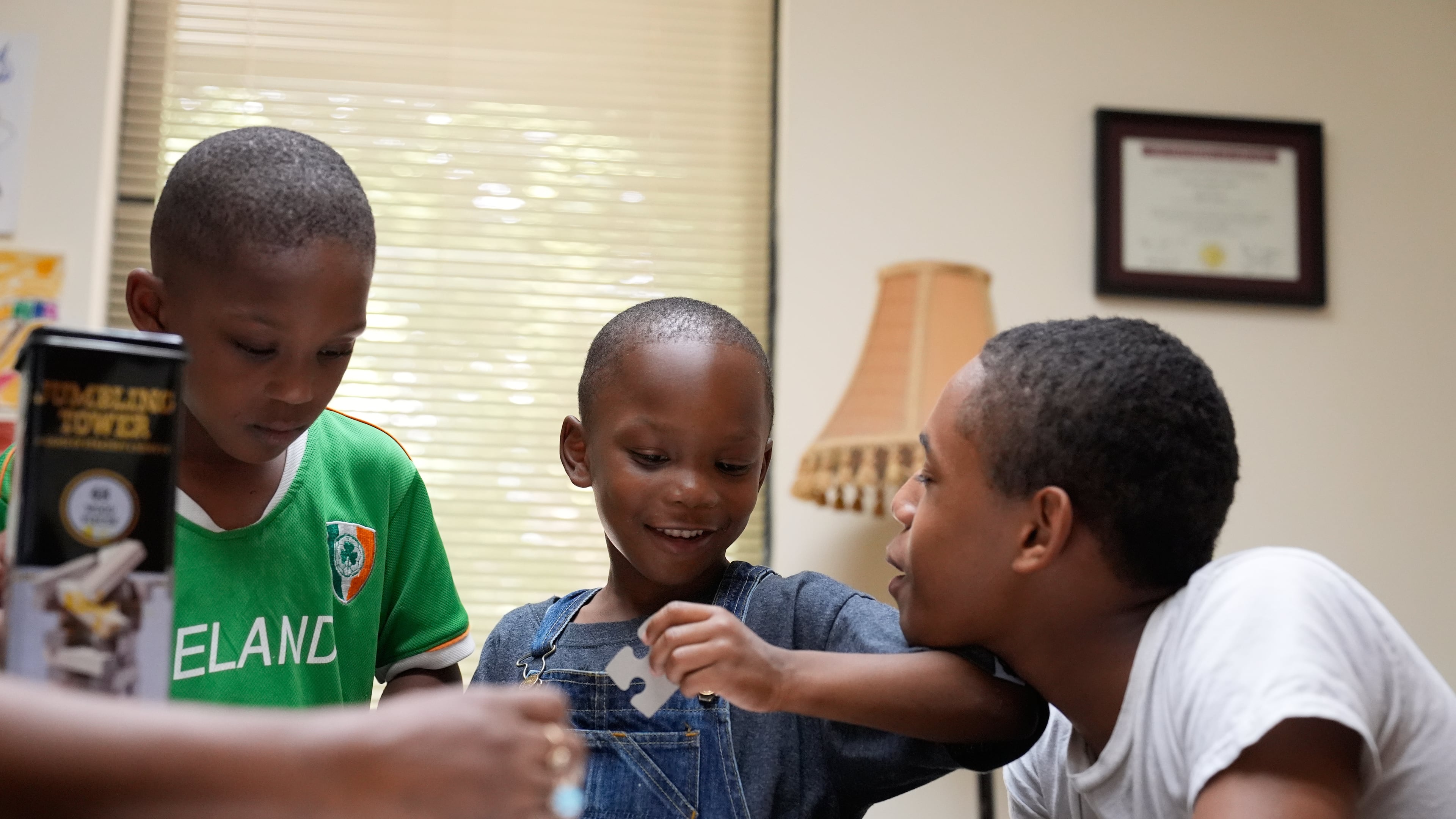 Derrick McNair-White, left, Malachi McNair-Nesbitt, and Elias Washington, right, do a puzzle together in family therapy on June 9, 2025, in Decatur, Ga. (AP Photo/Brynn Anderson)