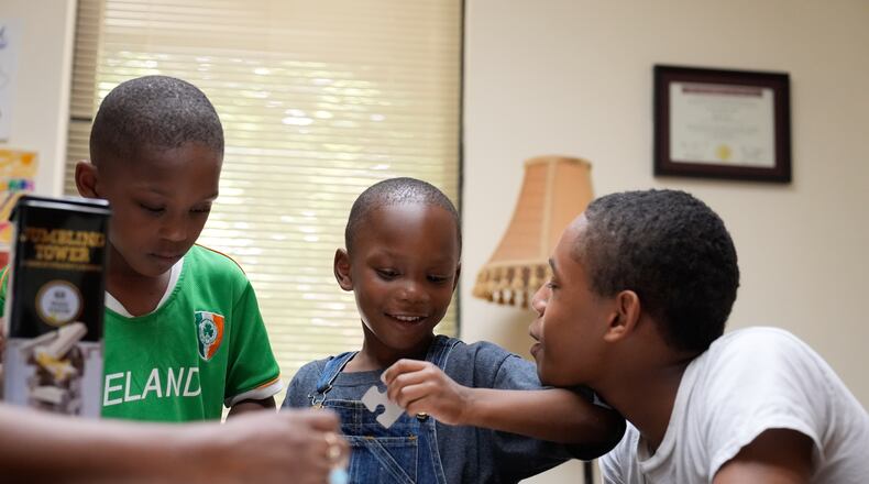 Derrick McNair-White, left, Malachi McNair-Nesbitt, and Elias Washington, right, do a puzzle together in family therapy on June 9, 2025, in Decatur, Ga. (AP Photo/Brynn Anderson)