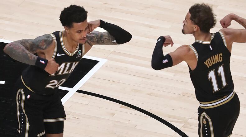 Hawks forward John Collins (left) and guard Trae Young flex after teaming up for a score against the Oklahoma City Thunder Thursday, March 18, 2021, at State Farm Arena in Atlanta. (Curtis Compton / Curtis.Compton@ajc.com)