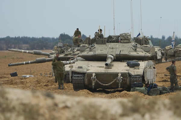 Israeli soldiers work on tanks and APCs at a staging area near the border with the Gaza Strip, in southern Israel, Thursday, May 15, 2025. (AP Photo/Ariel Schalit)