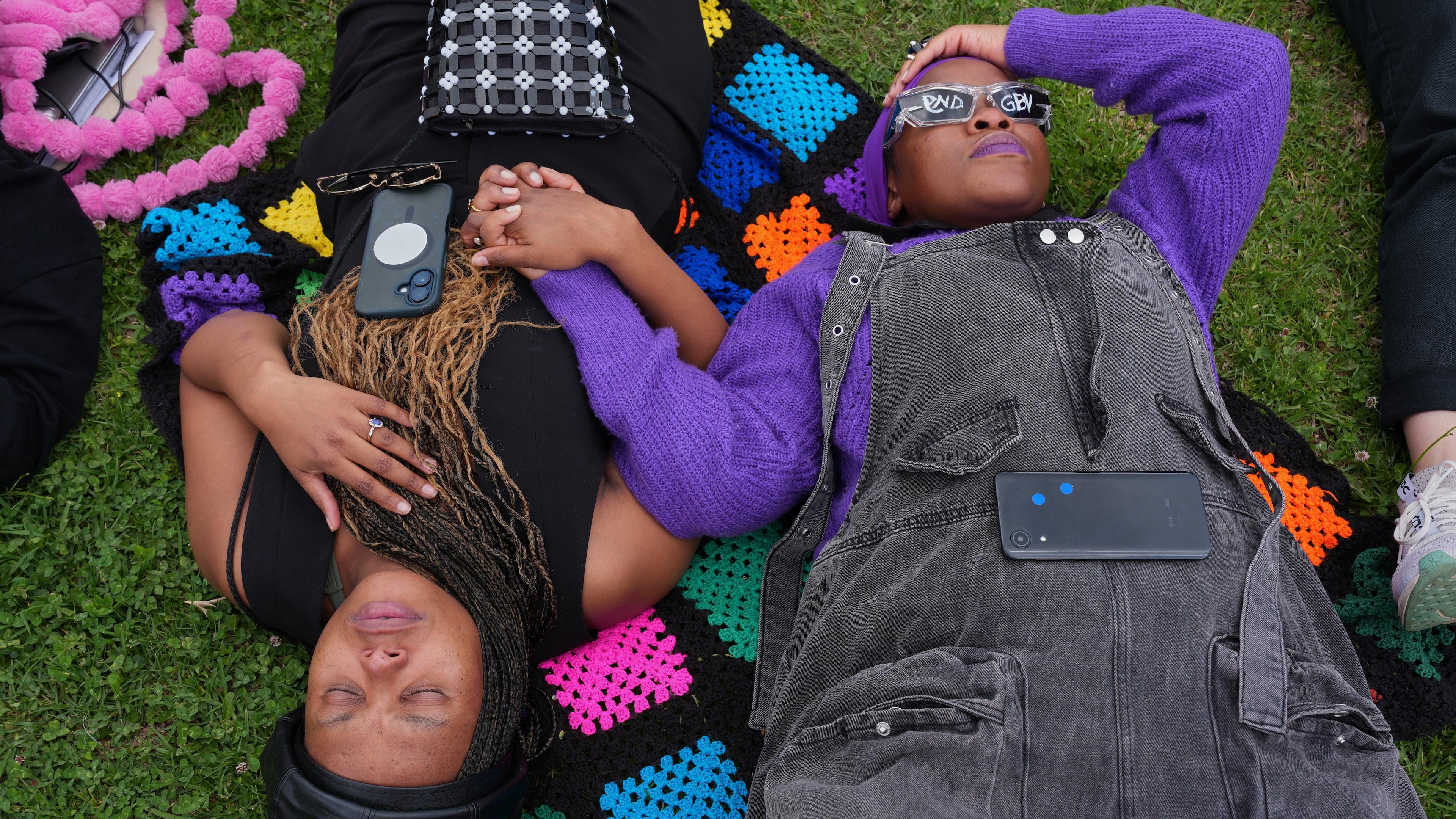 Participants hold hands as they lie on the ground during a gender-based violence protest at the forecourt of the botanical gardens in Johannesburg, South Africa, Friday, Nov. 21, 2025. (Misper Apawu)