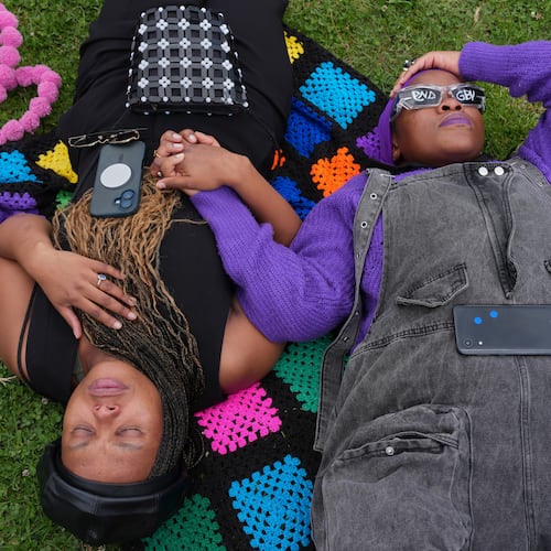 Participants hold hands as they lie on the ground during a gender-based violence protest at the forecourt of the botanical gardens in Johannesburg, South Africa, Friday, Nov. 21, 2025. (Misper Apawu)